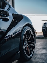 Rear view of a stylish coupe with shiny alloy wheels on smooth pavement.