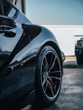 Close-up of a sleek black car with shiny alloy wheels reflecting sunlight.