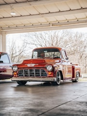 A shiny red truck being painted in a professional auto body shop.
