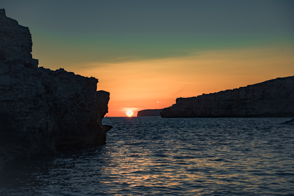 the sun is setting over the water off the coast