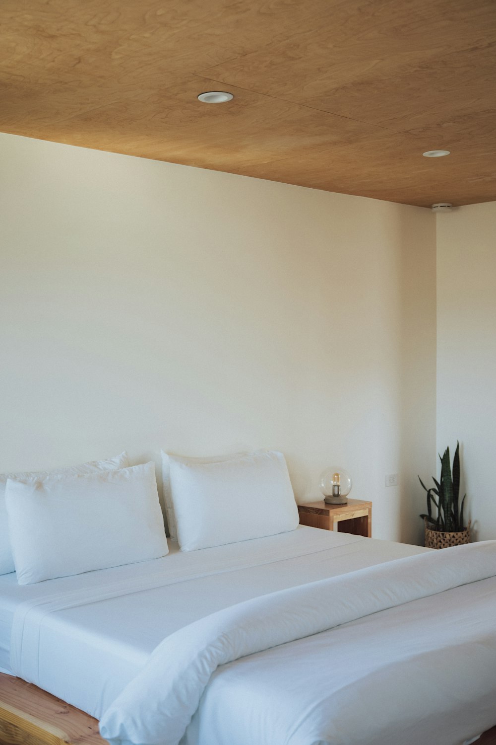 a bed with white sheets and pillows in a room