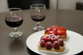 A rich red wine poured halfway in a glass beside a dark chocolate dessert