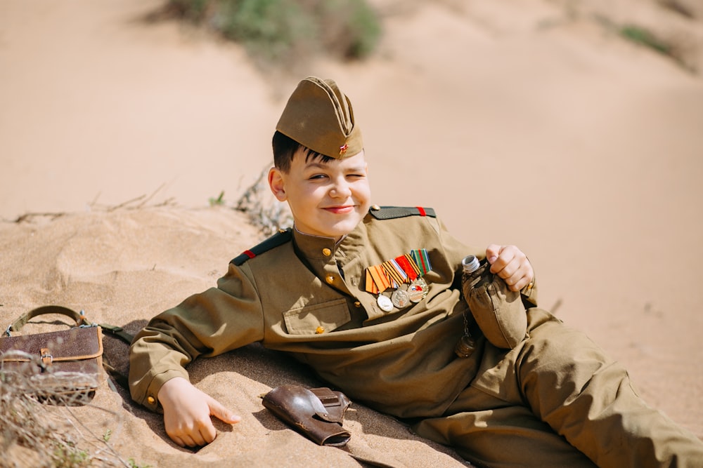 Un ragazzo in uniforme militare sdraiato sulla sabbia