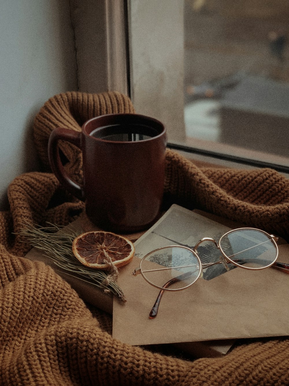 a cup of coffee and a pair of glasses on a blanket