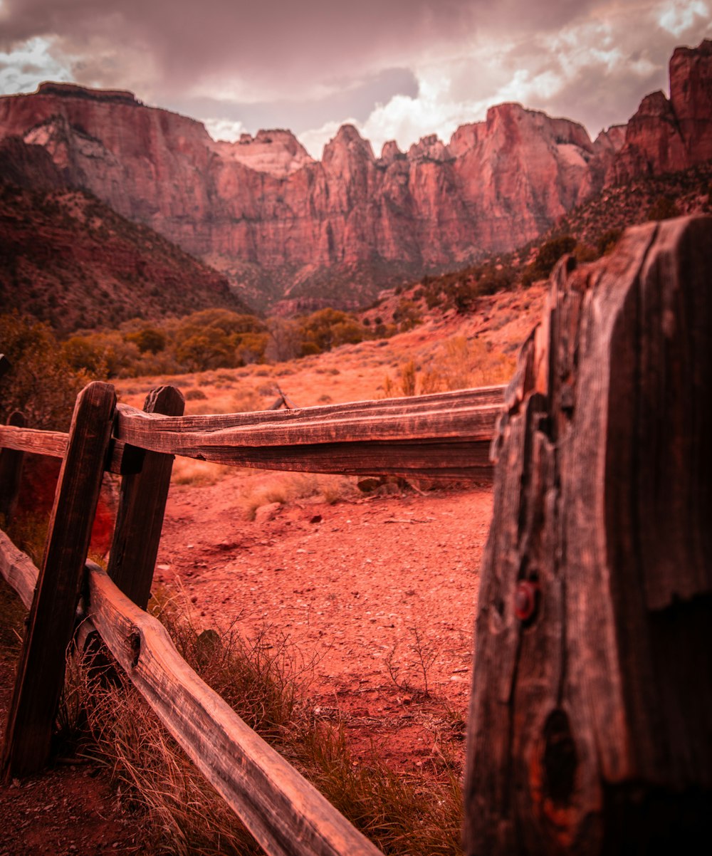 a wooden fence in front of a mountain range