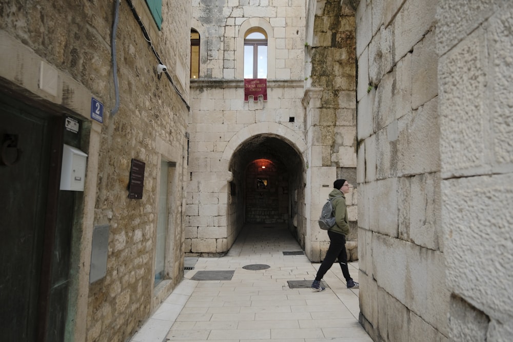 a man walking down a narrow alley way