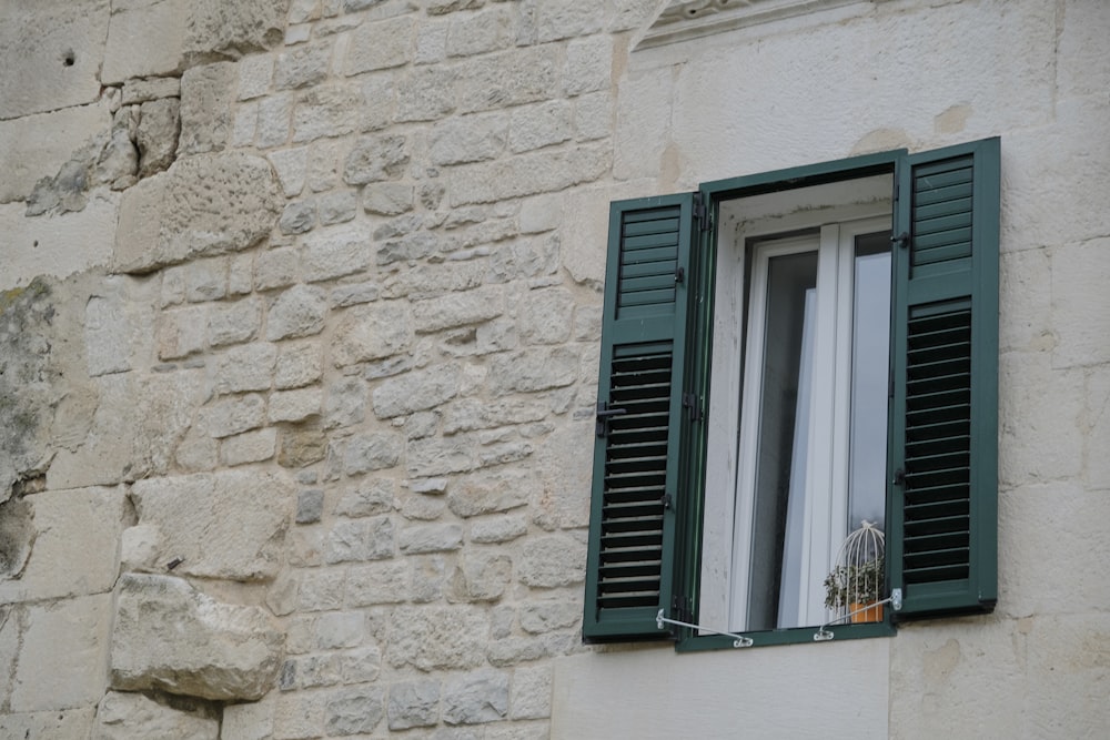 a window with green shutters on a stone building