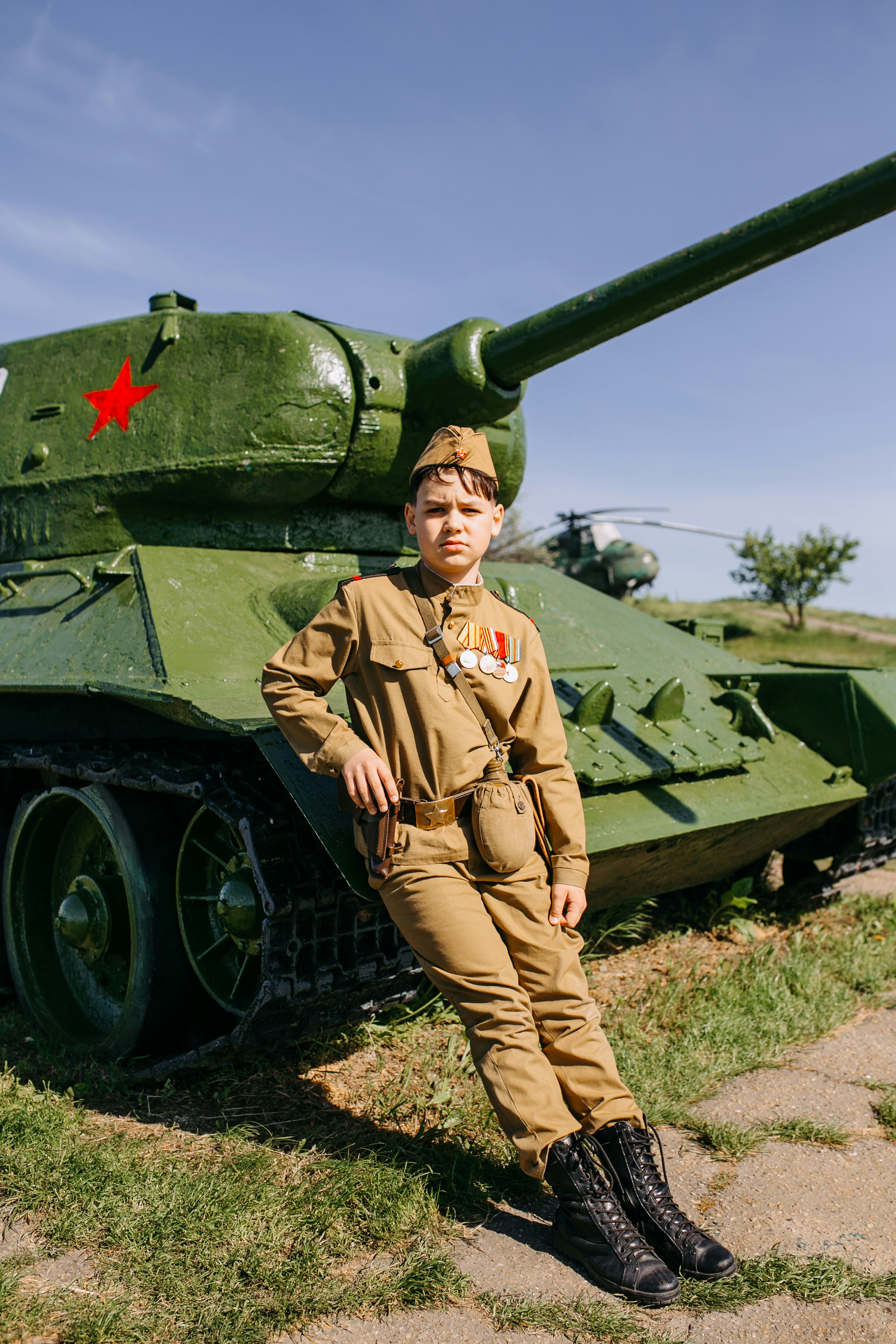 a boy in a military uniform standing next to a tank