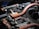 A close-up view of a circuit board featuring copper heat pipes, various electronic components, connectors, and chips. The copper elements stand out against the dark, intricate background of the circuit board.