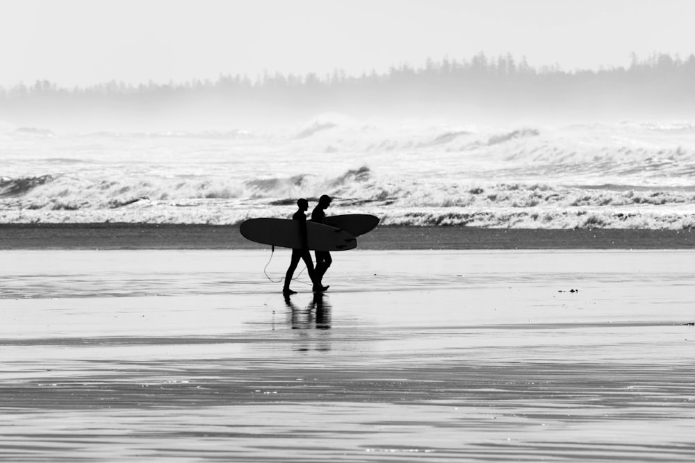 a couple of people holding surfboards on a beach