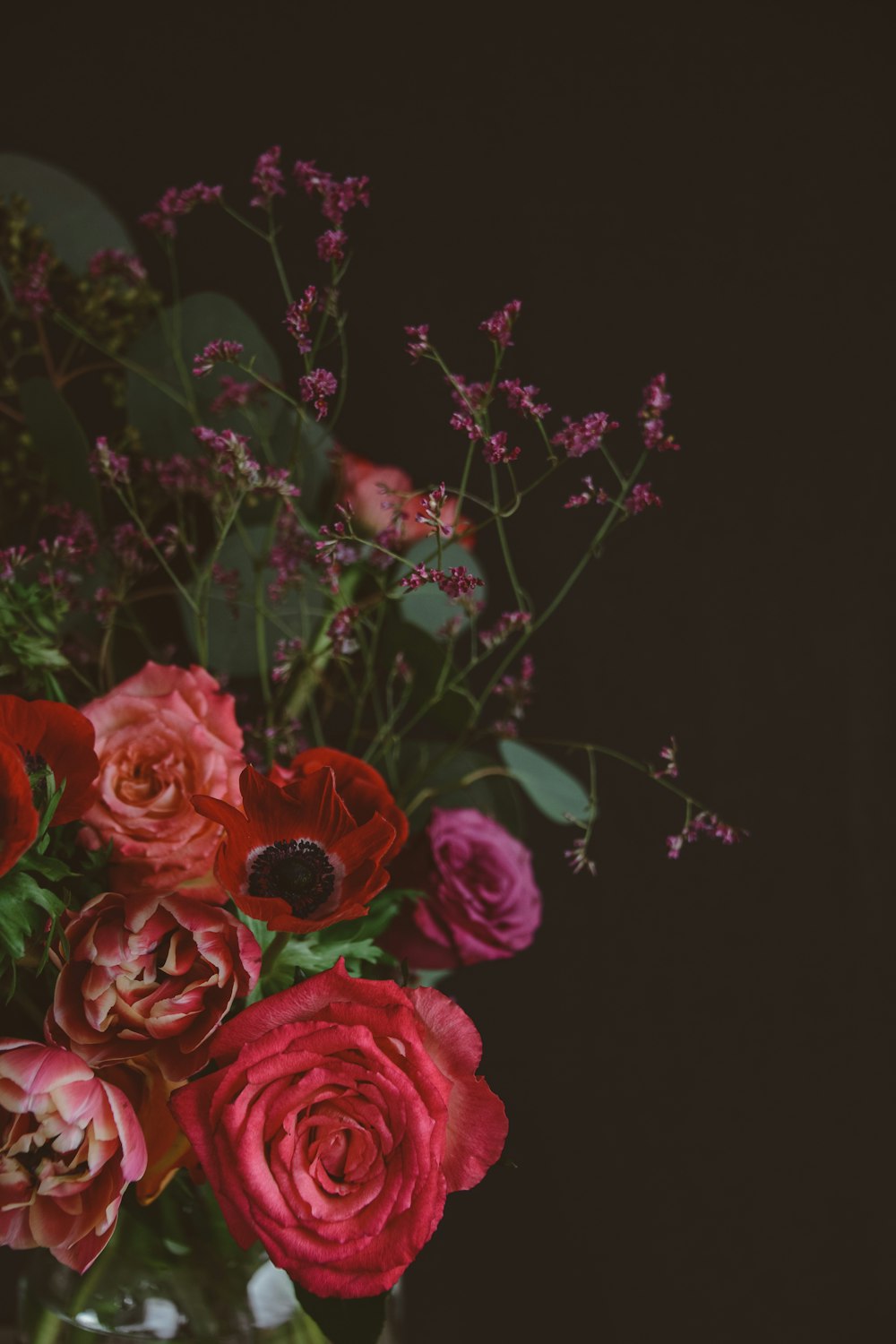 a vase filled with lots of red and pink flowers