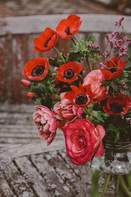 A colorful bouquet of mixed flowers arranged in a rustic vase