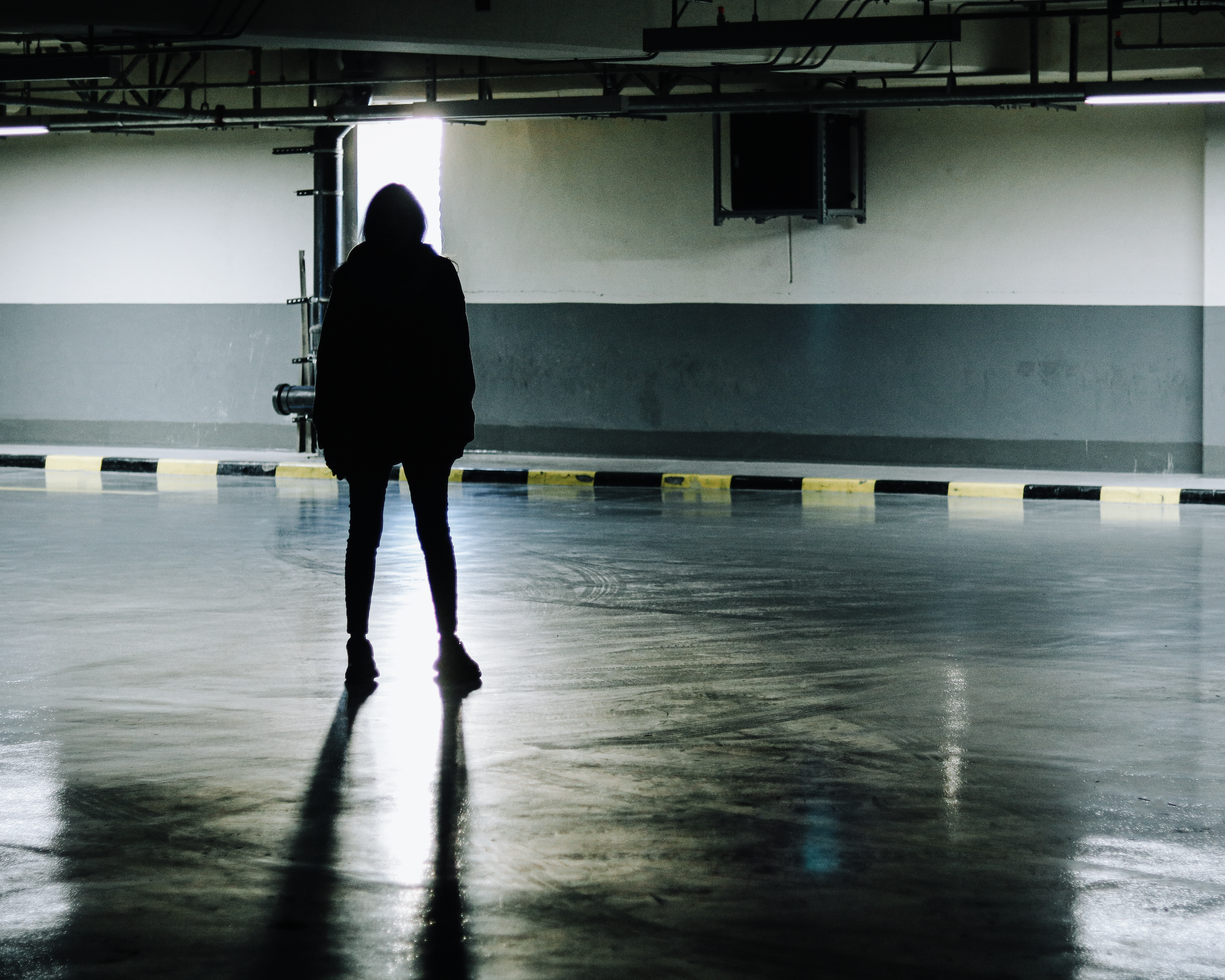 a person standing in a parking garage with their back to the camera
