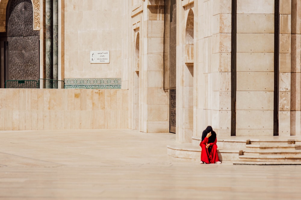 a woman in a red dress sitting on the ground