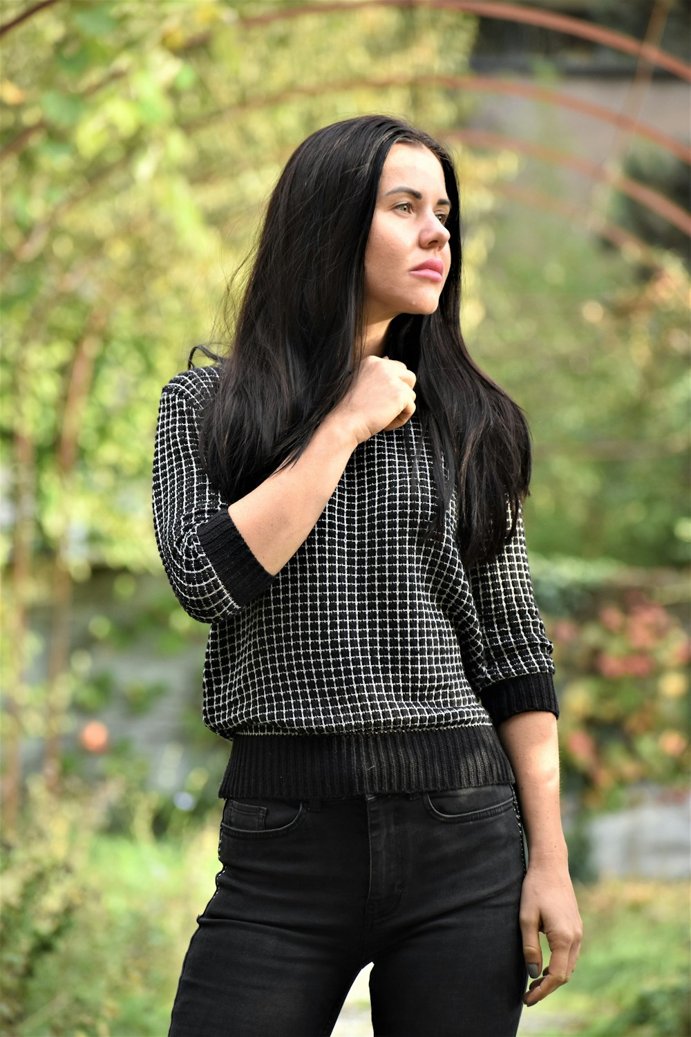 a woman with long black hair standing in a park