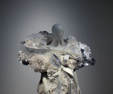 Beautiful quinceañera dress showcased on a mannequin surrounded by delicate floral arrangements.