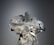 A mannequin is adorned with an elaborate and intricate dress featuring voluminous floral decorations and ribbons. The design includes shimmering elements and textured layers, creating a luxurious and artistic appearance.