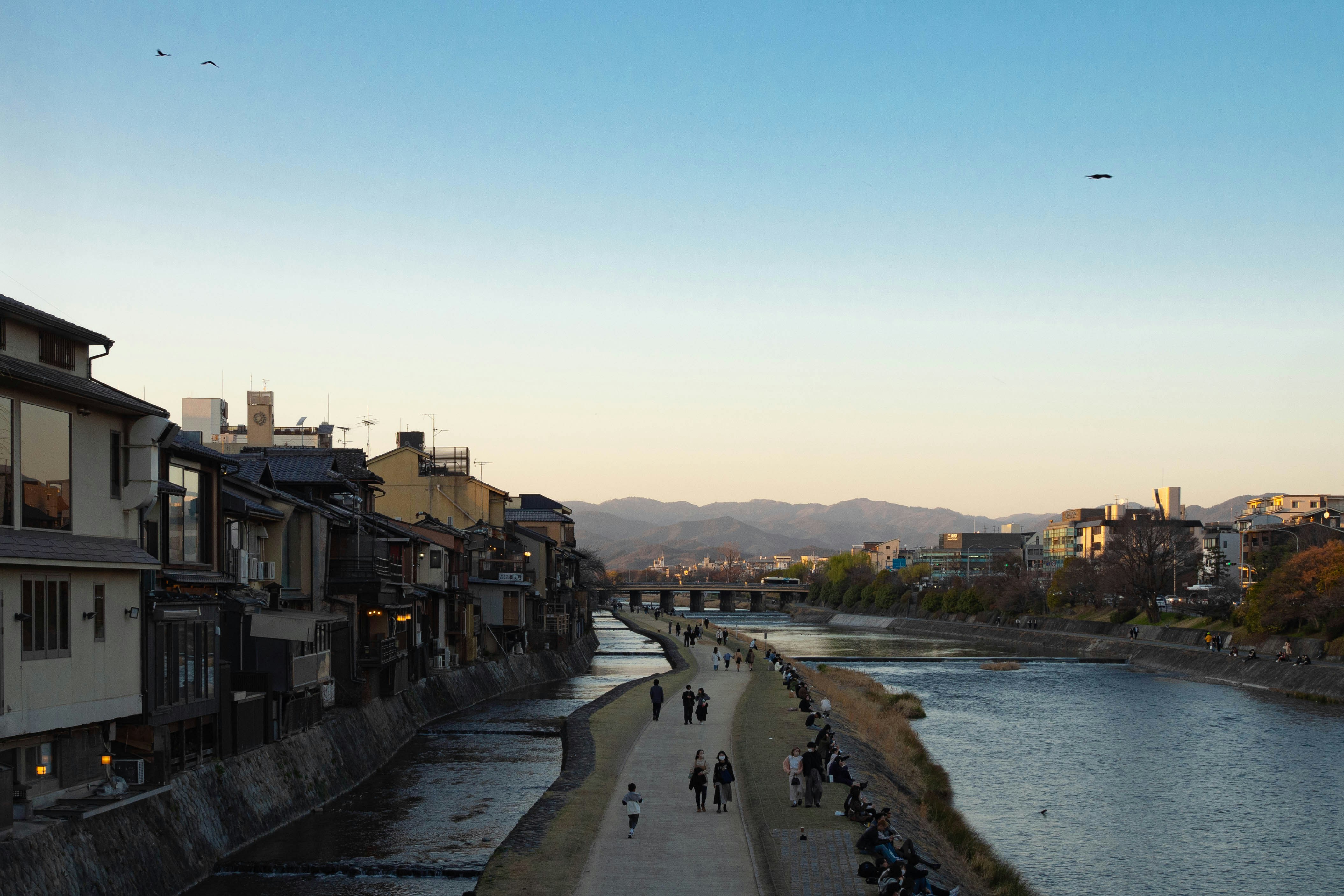 a group of people walking down a street next to a river
