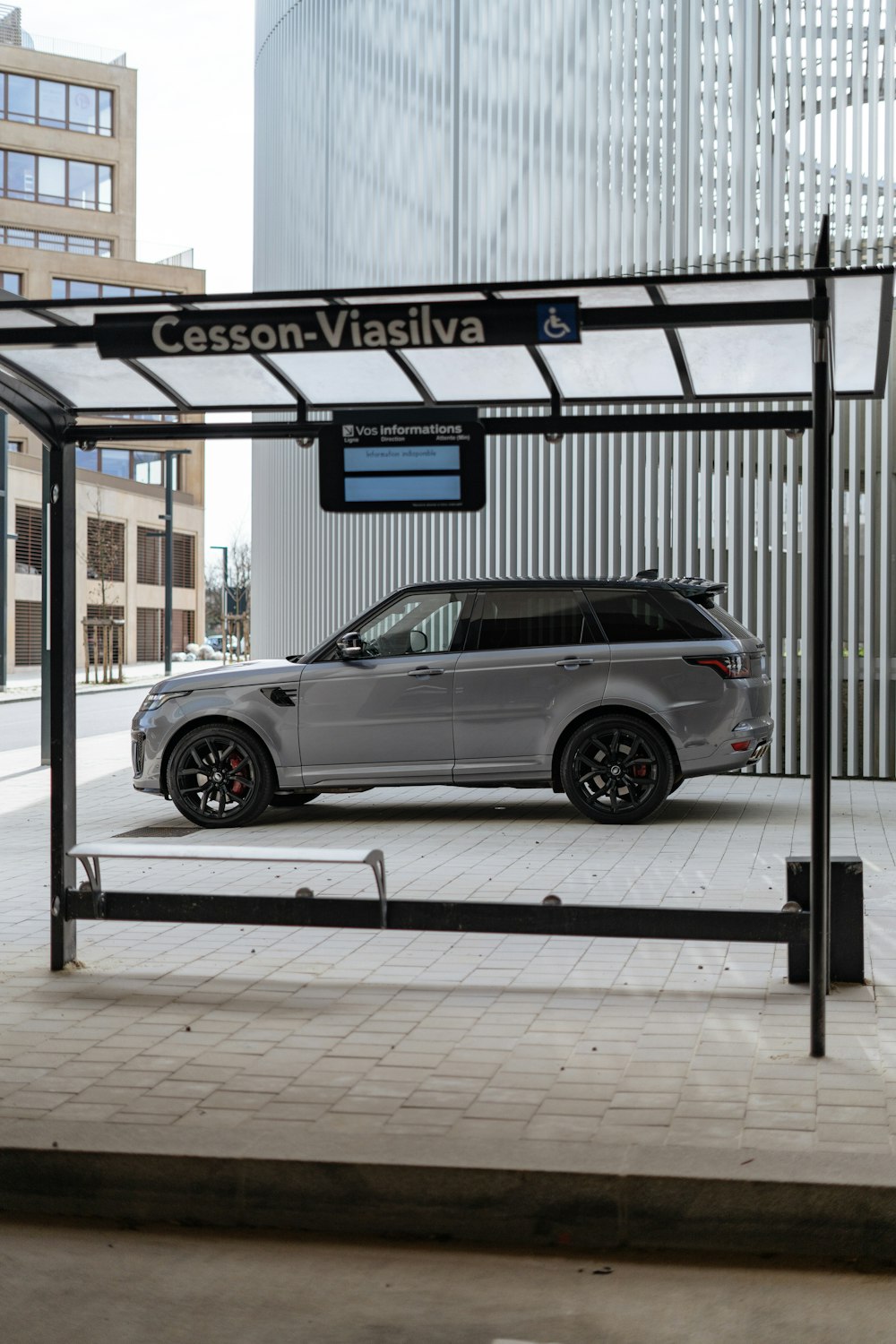 a silver range rover parked in front of a bus stop