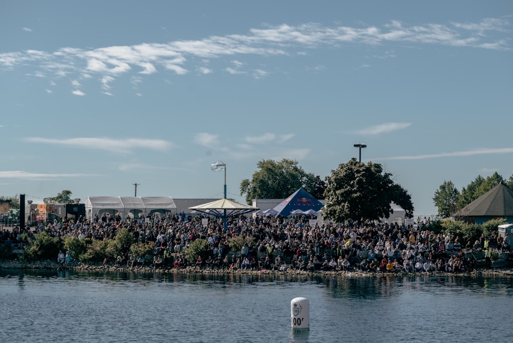 a large group of people sitting on the side of a lake