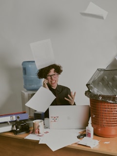 a person sitting at a desk with a laptop and papers