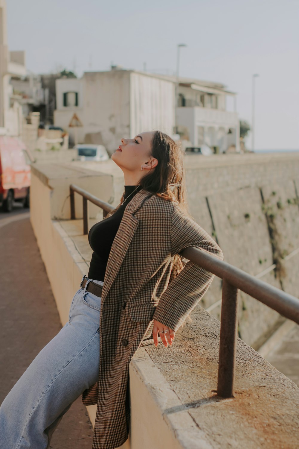 a woman leaning on a rail next to the ocean