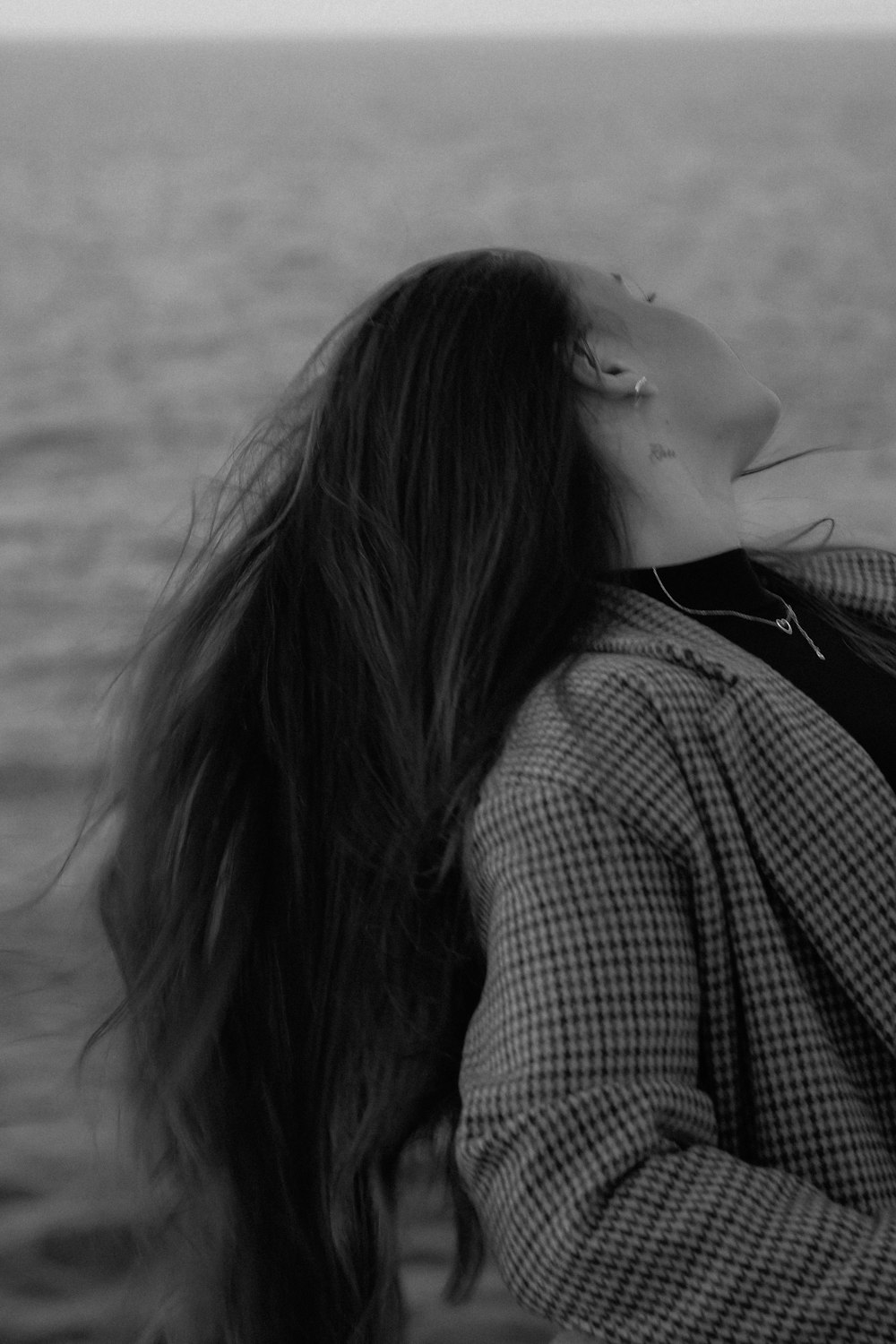 a woman with long hair standing in front of a body of water