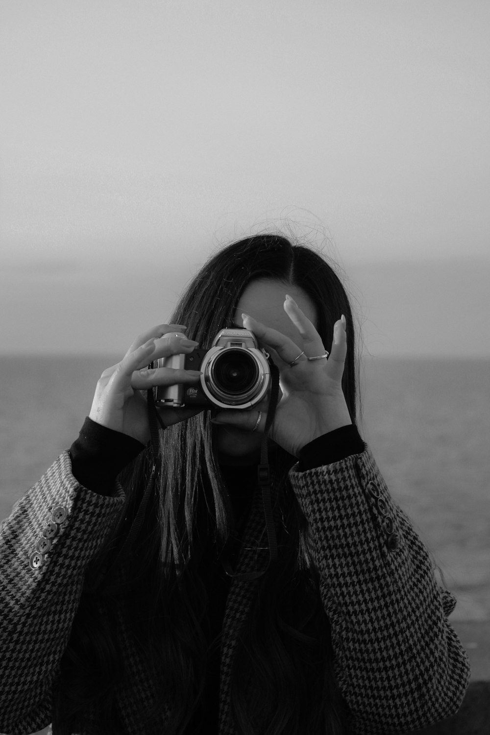 a woman taking a picture of the ocean with a camera