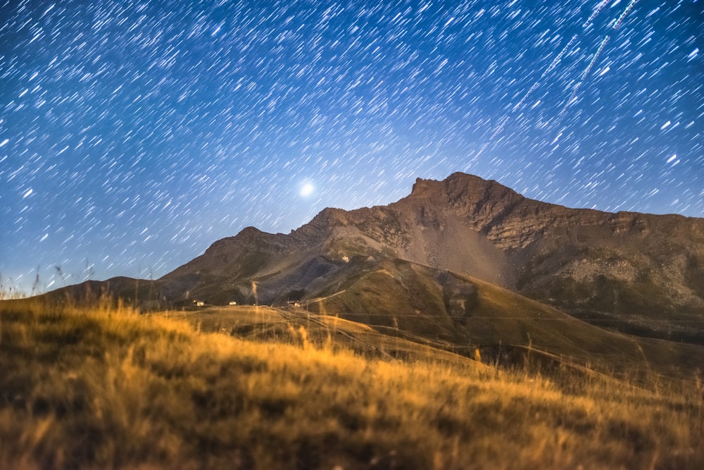 the night sky over a mountain range with stars in the sky