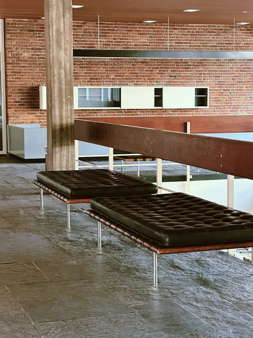 a long bench sitting in front of a brick wall