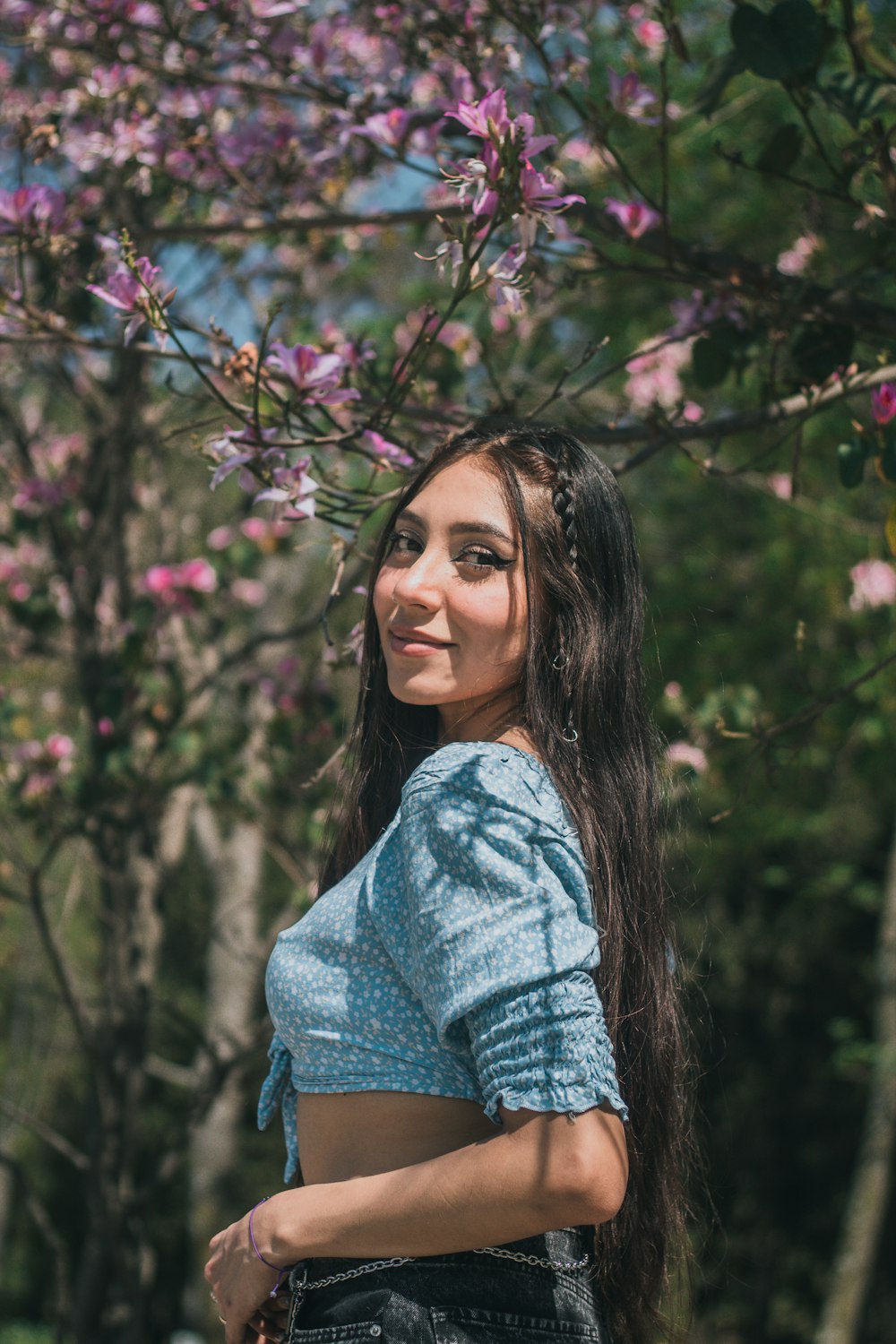 a woman with long hair standing in front of a tree