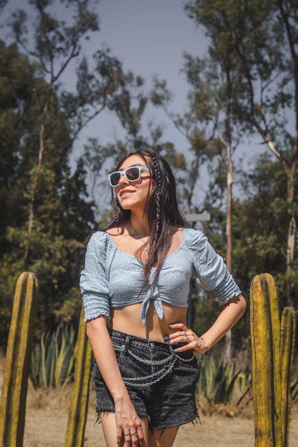 a woman standing in front of a cactus with her hands on her hips