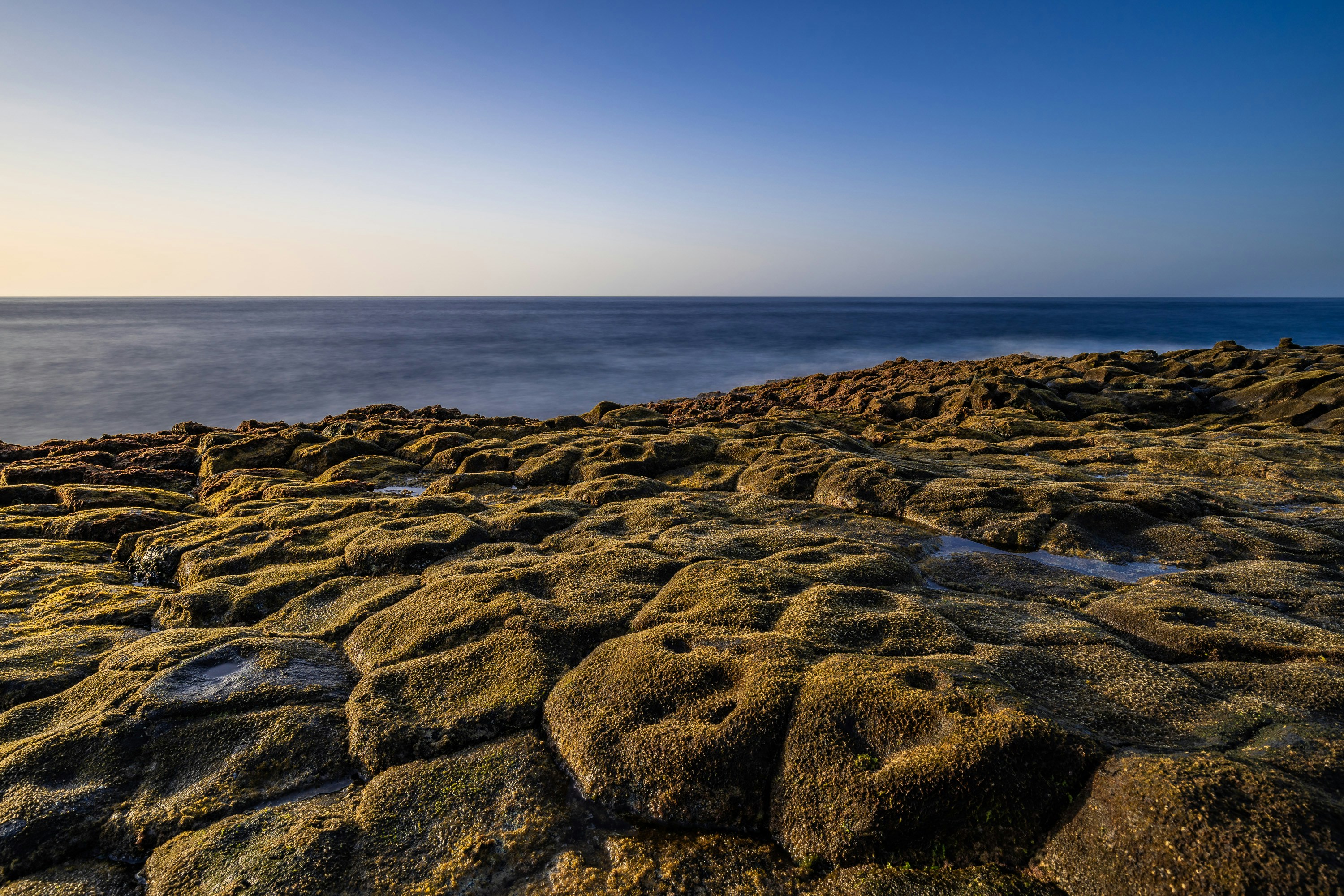 a rocky shore with a body of water in the distance