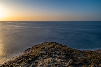 the sun is setting over the ocean on the horizon