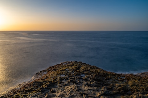 the sun is setting over the ocean on the horizon