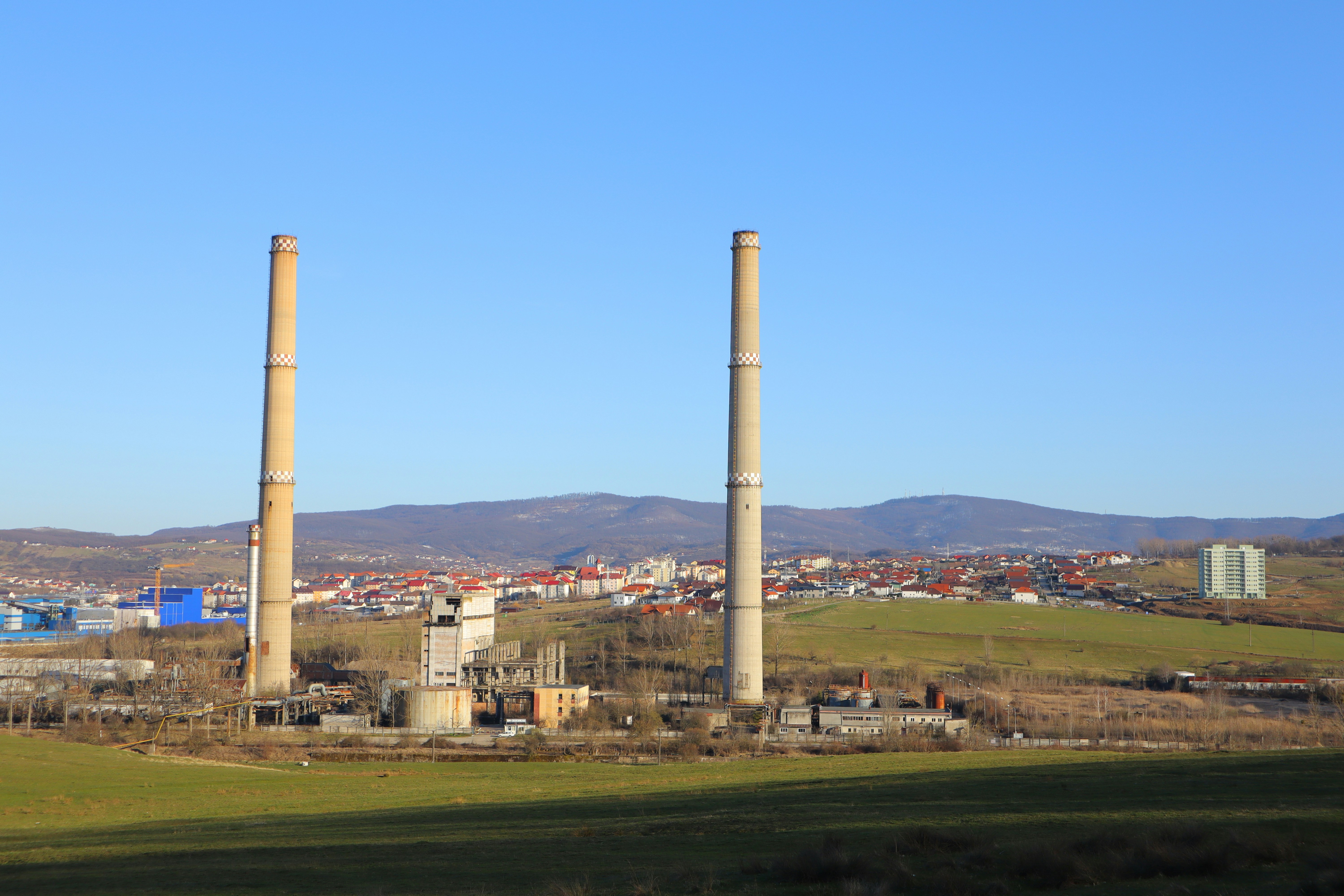 a factory with smoke stacks in the foreground