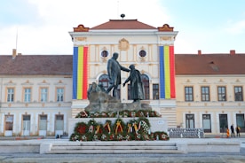 a statue of two men shaking hands in front of a building