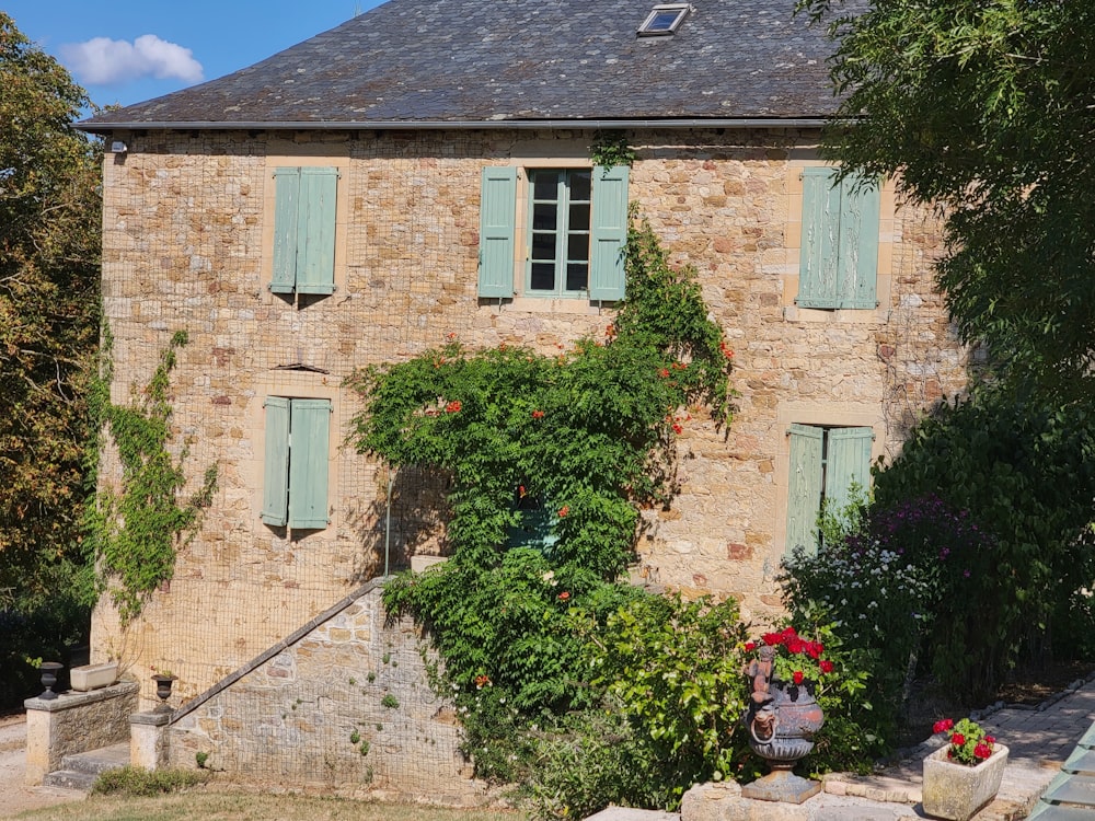 an old building with green shutters and flowers in front of it