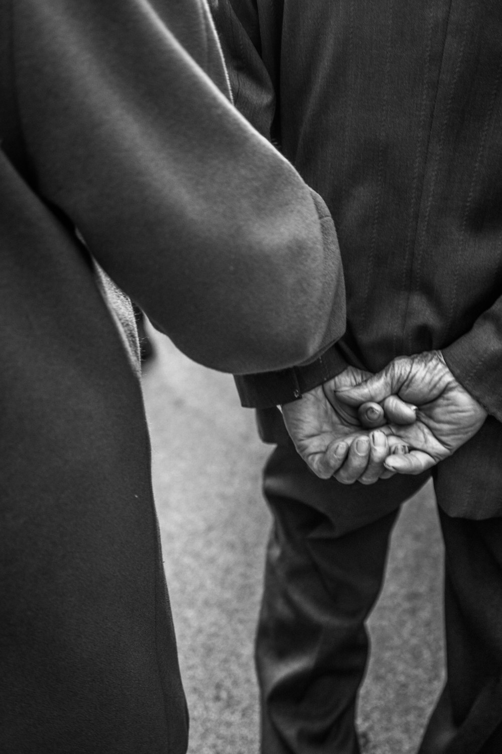 a black and white photo of two people holding hands