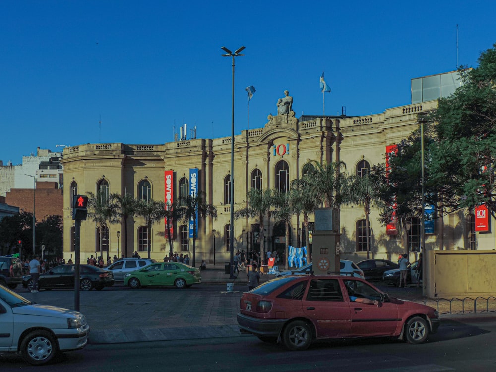 a red car driving down a street next to a tall building