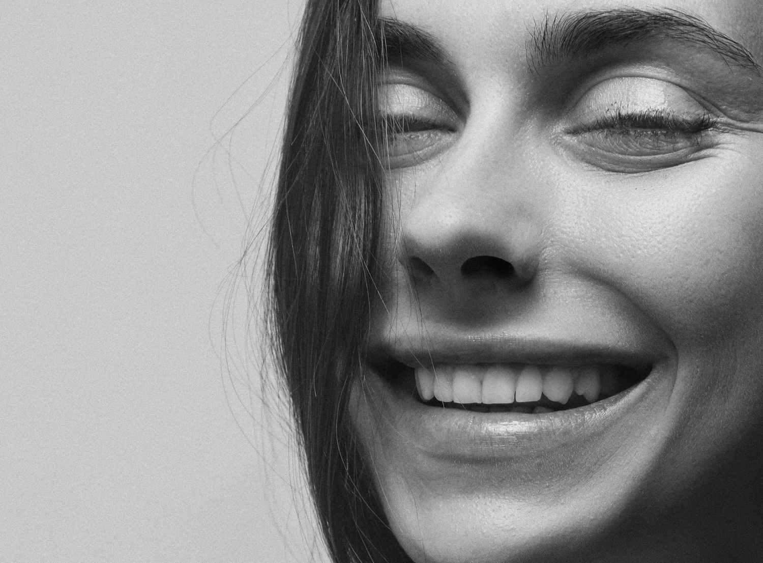 Close-up smiling portrait clearly showing the outer eye corner and cheek area before crow's feet botulinum toxin consultation