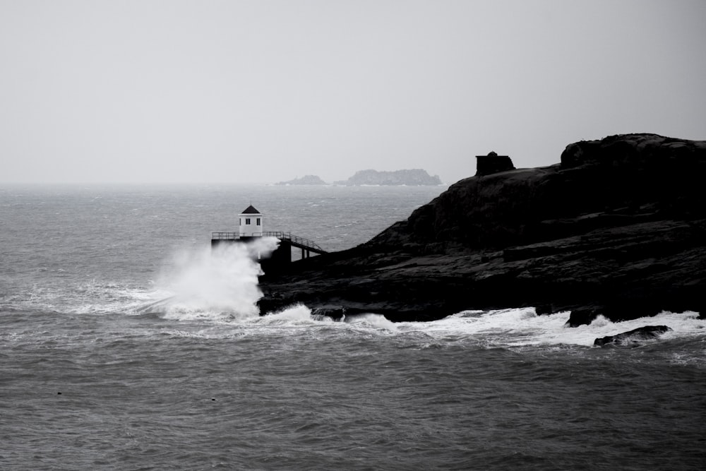 a black and white photo of a lighthouse in the ocean