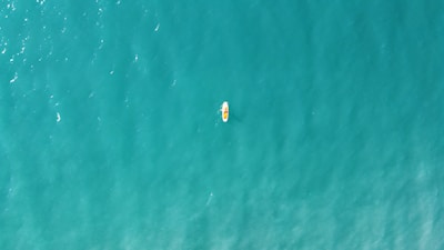 A kayaker paddling through crystal-clear turquoise waters surrounded by lush green islands.