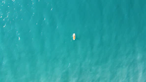 An adventurous male influencer kayaking through turquoise waters surrounded by cliffs.