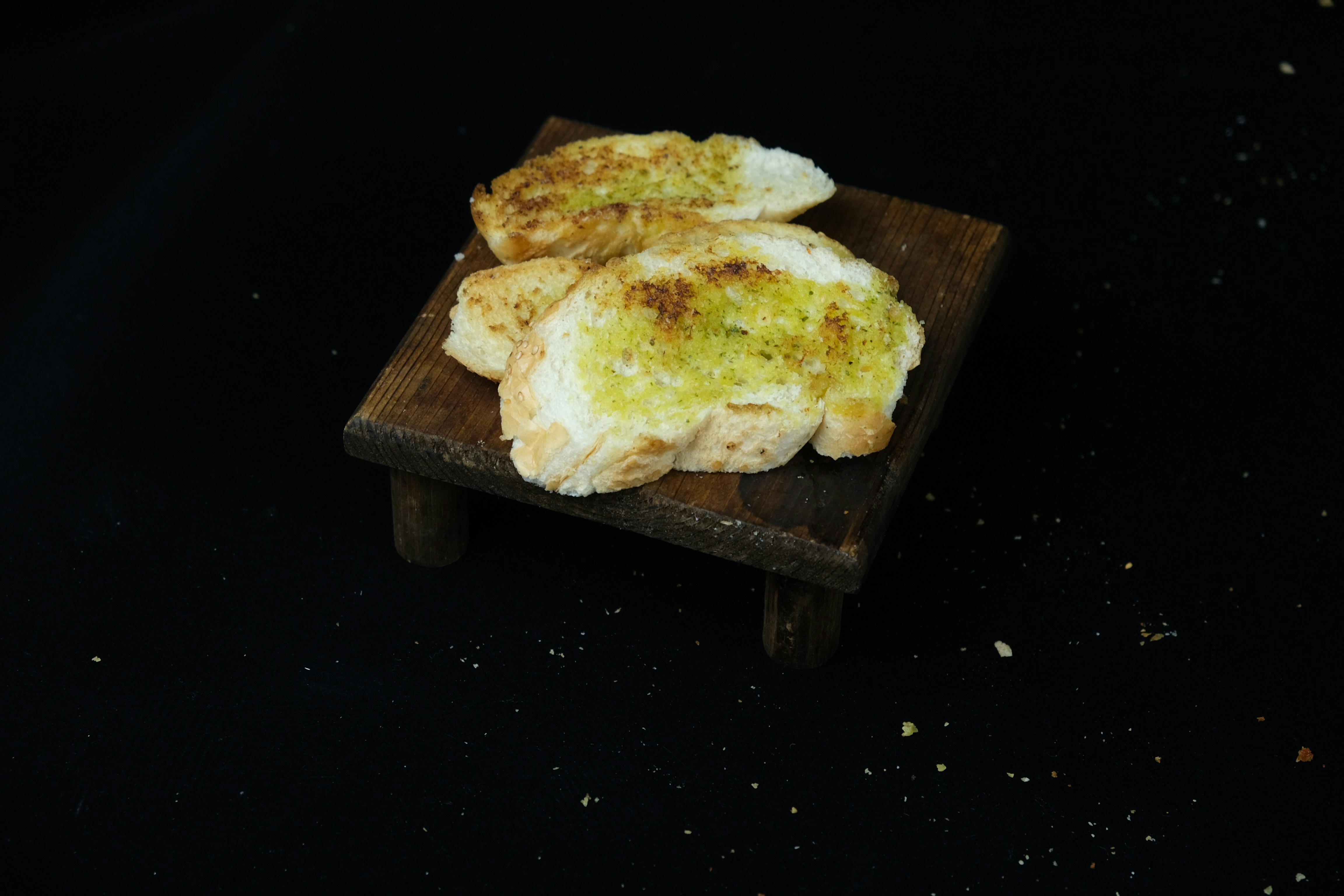 Toasted garlic bread slices with herb butter on wooden board