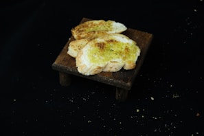 Stack of warm, freshly baked garlic breadsticks with a side of marinara sauce on a wooden board.
