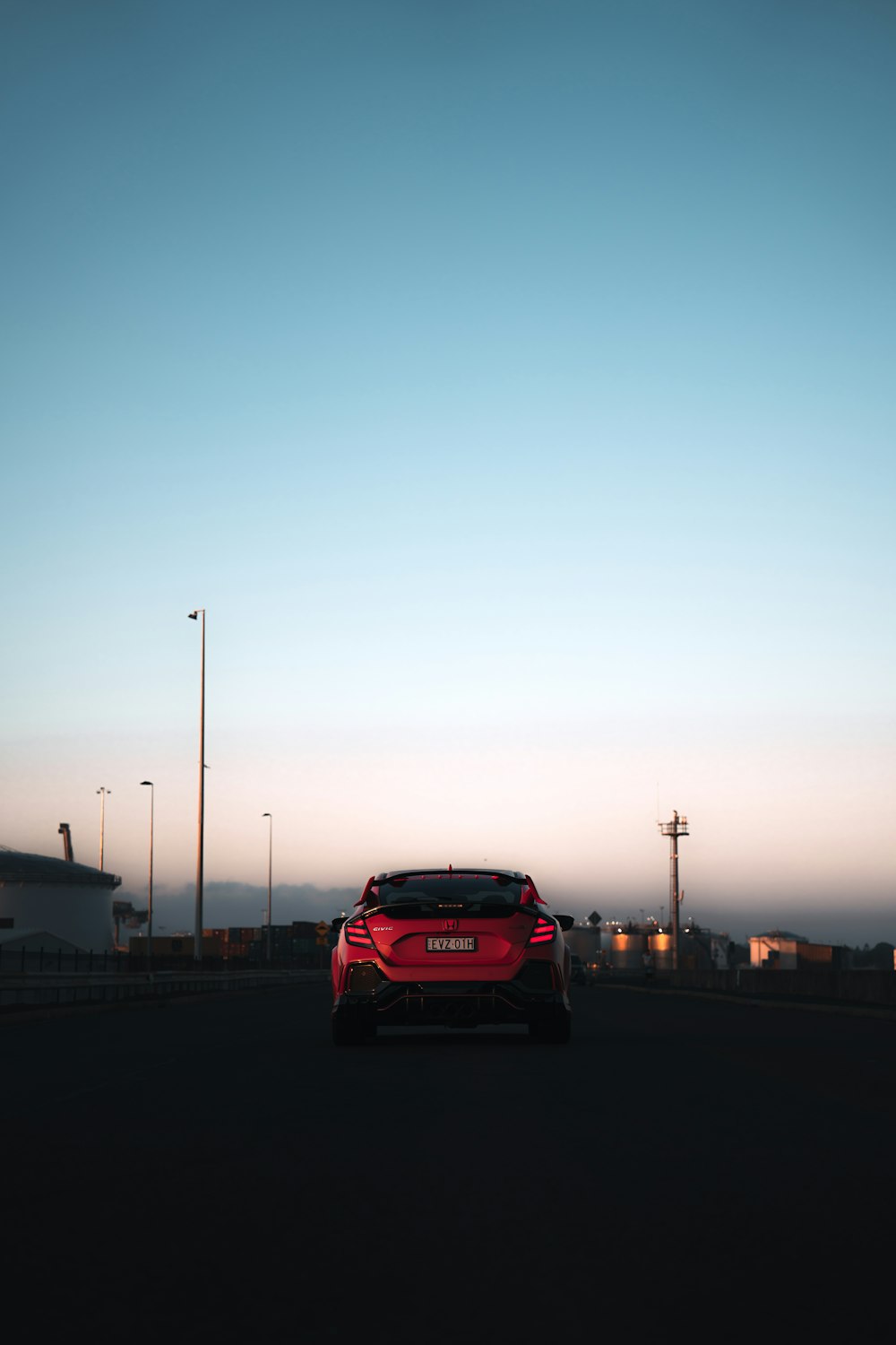 a red car driving down a street next to tall buildings