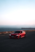 Red sports car shining under the sun on a coastal road