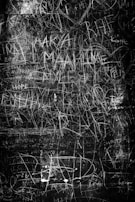 Chaotic scribbles and faded words layered over a dimly lit room, hinting at the fragmented thoughts within.