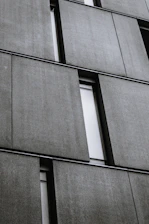 Workers installing large precast concrete panels on a modern warehouse structure at a construction site.